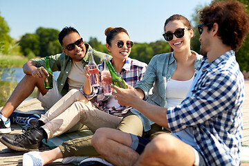 Image showing friends drinking beer and cider on lake pier