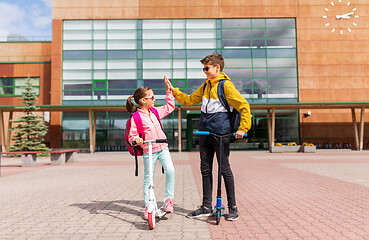 Image showing school kids riding scooters and making high five