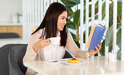 Image showing woman drinking coffee and reading book at cafe