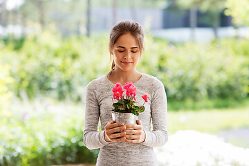 Image showing young woman with cyclamen flowers at summer garden