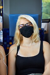 Image showing Young woman on a train wearing masks