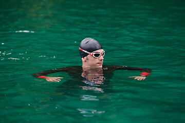 Image showing triathlon athlete swimming on lake wearing wetsuit