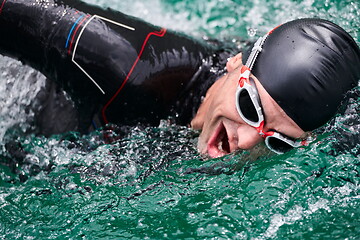 Image showing triathlon athlete swimming on lake wearing wetsuit