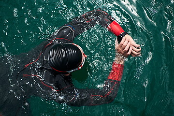 Image showing triathlon athlete swimming on lake setting smartwatch