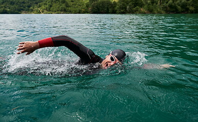 Image showing triathlon athlete swimming on lake wearing wetsuit