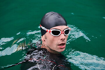 Image showing triathlon athlete swimming on lake wearing wetsuit