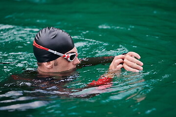 Image showing triathlon athlete swimming on lake setting smartwatch