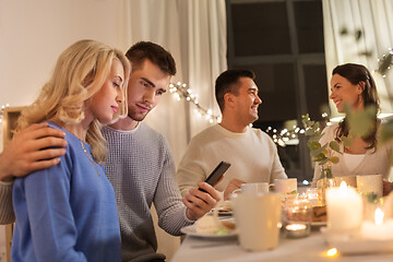 Image showing happy couple with smartphone at family tea party