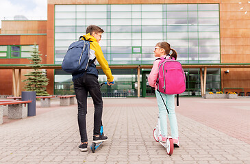 Image showing school children with backpacks riding scooters