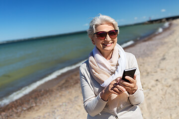 Image showing senior woman using smartphone on beach