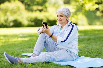 Image showing sporty senior woman with earphones and smartphone