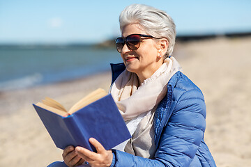 Image showing happy senior woman reading book on summer beach