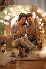 Image showing couple drinking coffee or tea in kids tent at home