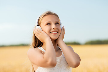 Image showing happy girl in headphones on cereal field in summer