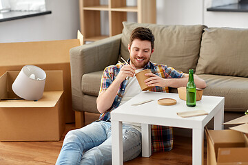 Image showing smiling man eating takeaway food at new home