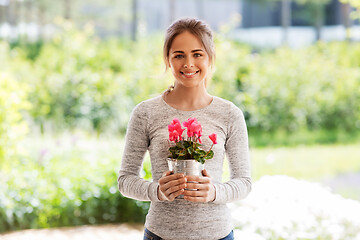 Image showing young woman with cyclamen flowers at summer garden