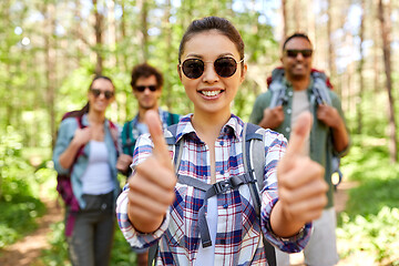 Image showing friends with backpacks showing thumbs up in forest