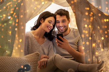 Image showing happy couple with smartphone in kids tent at home