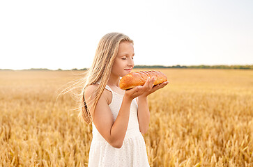 Image showing girl smelling loaf of white bread on cereal field