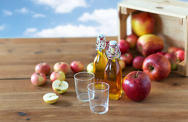 Image showing glasses and bottles of apple juice on wooden table