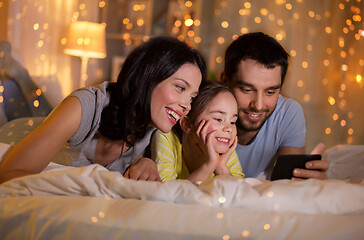 Image showing happy family with smartphone in bed at night