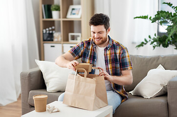 Image showing smiling man unpacking takeaway food at home