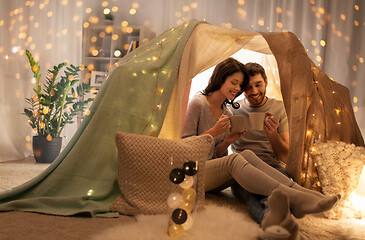 Image showing couple drinking coffee or tea in kids tent at home