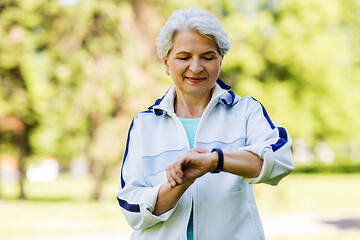 Image showing sporty senior woman with fitness tracker in park