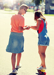 Image showing teenage couple riding skateboard on city street