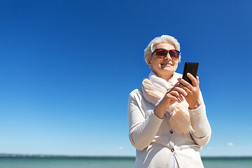 Image showing senior woman using smartphone on beach