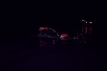 Image showing triathlon athlete swimming in dark night wearing wetsuit