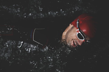 Image showing triathlon athlete swimming in dark night wearing wetsuit