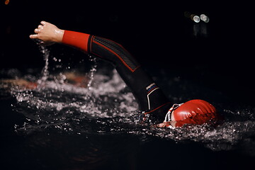 Image showing triathlon athlete swimming in dark night wearing wetsuit