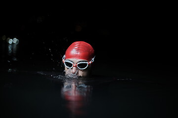 Image showing authentic triathlete swimmer having a break during hard training on night