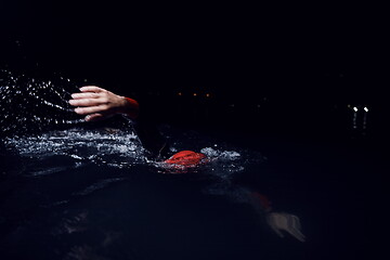 Image showing triathlon athlete swimming in dark night wearing wetsuit