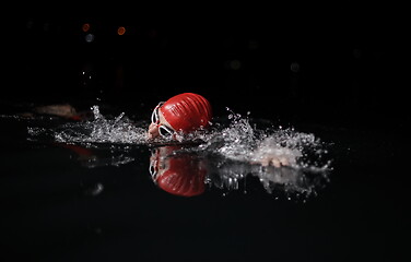 Image showing triathlon athlete swimming in dark night wearing wetsuit