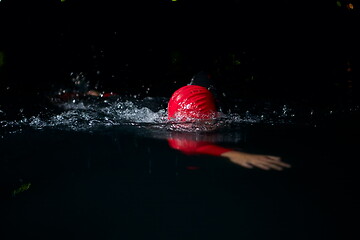 Image showing triathlon athlete swimming in dark night wearing wetsuit