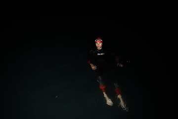 Image showing triathlon athlete swimming in dark night wearing wetsuit