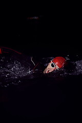 Image showing triathlon athlete swimming in dark night wearing wetsuit