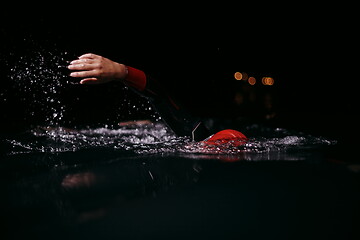 Image showing triathlon athlete swimming in dark night wearing wetsuit