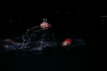 Image showing triathlon athlete swimming in dark night wearing wetsuit