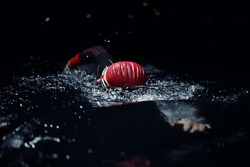 Image showing triathlon athlete swimming in dark night wearing wetsuit