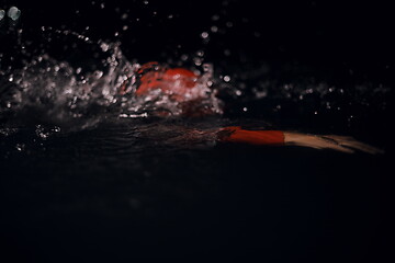 Image showing triathlon athlete swimming in dark night wearing wetsuit