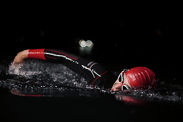 Image showing triathlon athlete swimming in dark night wearing wetsuit