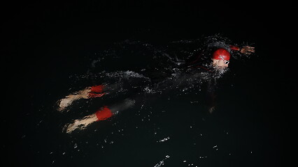 Image showing triathlon athlete swimming in dark night wearing wetsuit