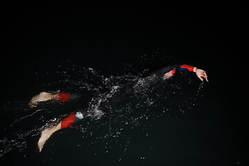 Image showing triathlon athlete swimming in dark night wearing wetsuit