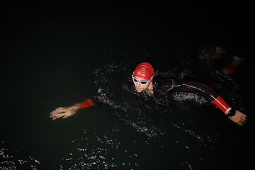 Image showing triathlon athlete swimming in dark night wearing wetsuit