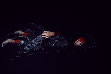 Image showing triathlon athlete swimming in dark night wearing wetsuit