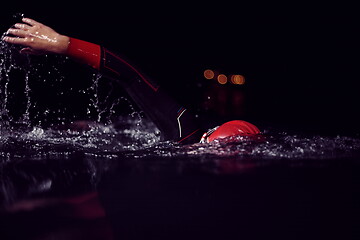 Image showing triathlon athlete swimming in dark night wearing wetsuit