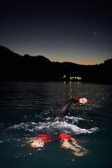 Image showing triathlon athlete swimming in dark night wearing wetsuit